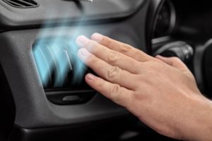 Driver checking flow of cold air from conditioning system in car