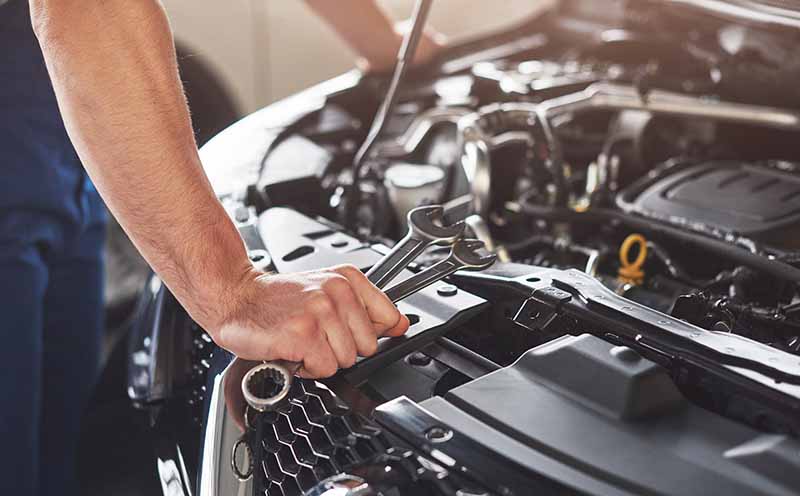 Oil Changes & Car Maintenance Services in Brook Park, OH Picture showing muscular car service worker repairing vehicle.